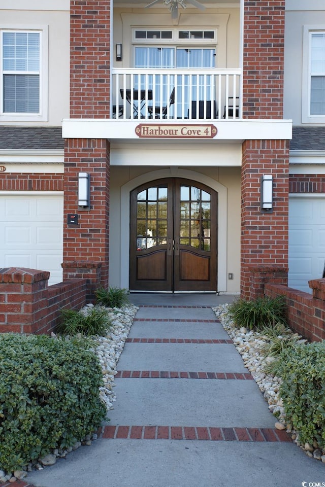 view of exterior entry with french doors, a balcony, and a garage