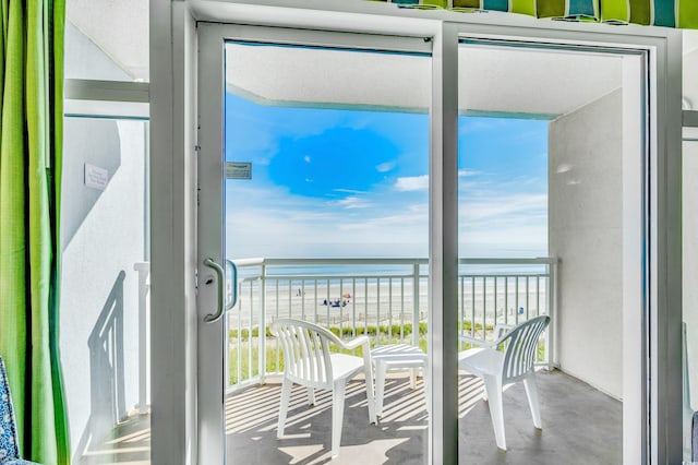 balcony with a water view and a view of the beach