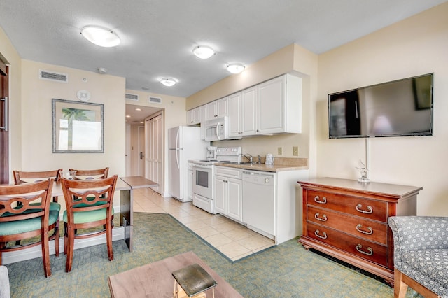 kitchen with white cabinetry, sink, light tile patterned floors, and white appliances