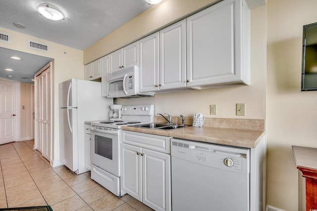 kitchen featuring white cabinetry, sink, light tile patterned flooring, and white appliances