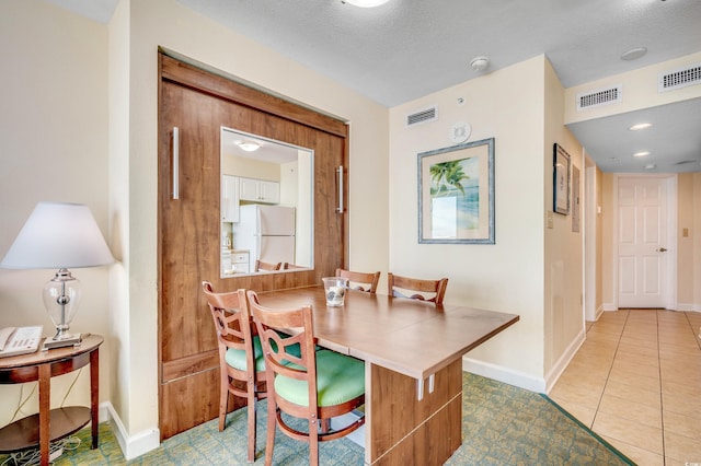 dining space with light tile patterned floors and a textured ceiling