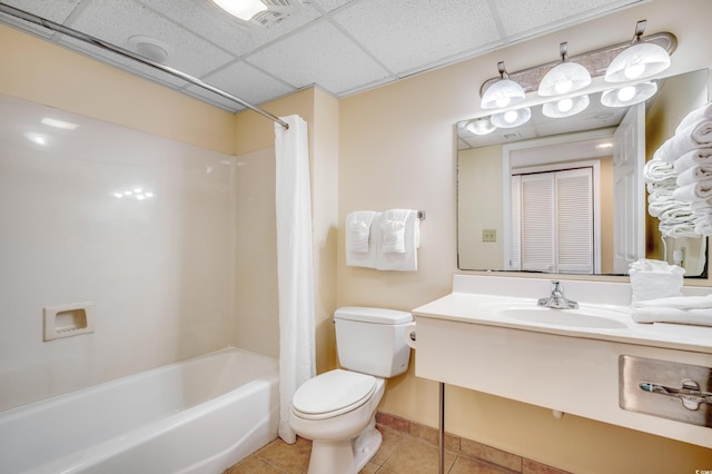 full bathroom with a paneled ceiling, tile patterned flooring, shower / tub combo, vanity, and toilet