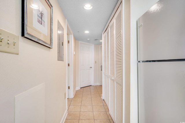 hall featuring light tile patterned floors, electric panel, and a textured ceiling