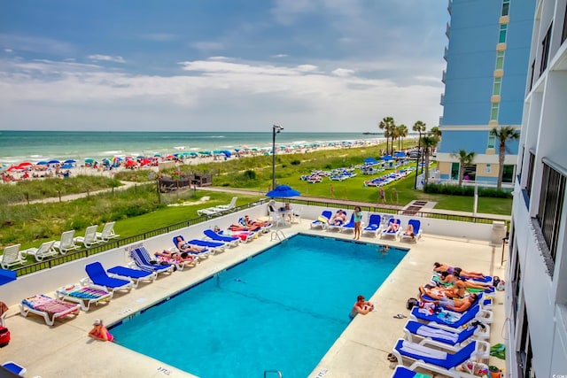 view of pool with a water view, a beach view, and a patio area