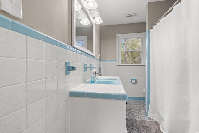 bathroom with vanity and tile walls