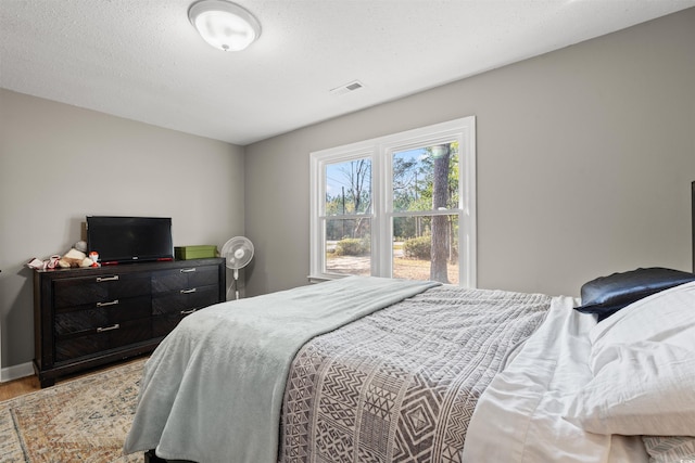 bedroom with light hardwood / wood-style floors and a textured ceiling