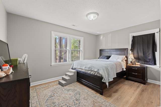 bedroom featuring a textured ceiling and light hardwood / wood-style floors