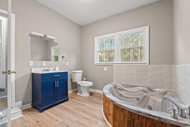 bathroom featuring vanity, a bathing tub, hardwood / wood-style flooring, toilet, and a textured ceiling