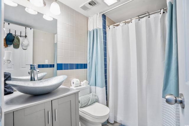 bathroom with vanity, a shower with shower curtain, tile walls, and toilet