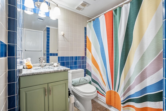 bathroom featuring tile patterned flooring, crown molding, toilet, vanity, and tile walls