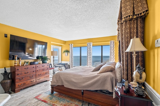 bedroom with a water view, wood-type flooring, and a textured ceiling