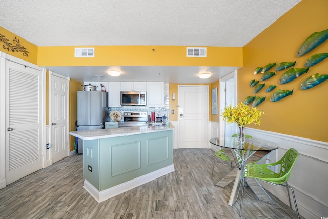 kitchen with sink, a textured ceiling, light hardwood / wood-style floors, white cabinetry, and stainless steel appliances