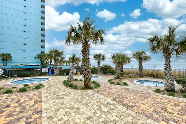 view of pool with a water view and a hot tub