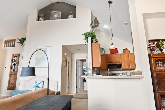 kitchen featuring kitchen peninsula, decorative light fixtures, and high vaulted ceiling