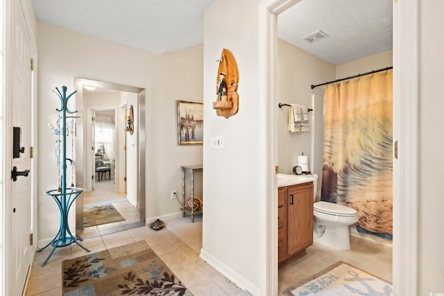 bathroom with toilet, vanity, tile patterned floors, and curtained shower