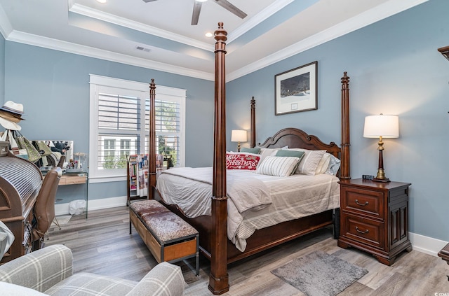 bedroom with ceiling fan, light wood-type flooring, crown molding, and a tray ceiling