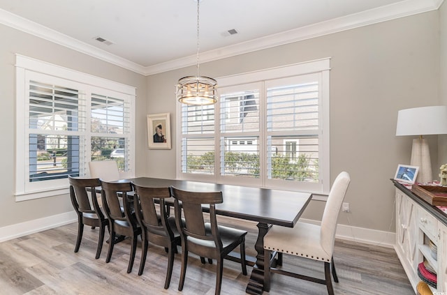 dining space with hardwood / wood-style floors, a notable chandelier, and ornamental molding