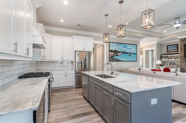 kitchen with white cabinets, decorative light fixtures, a center island with sink, and sink