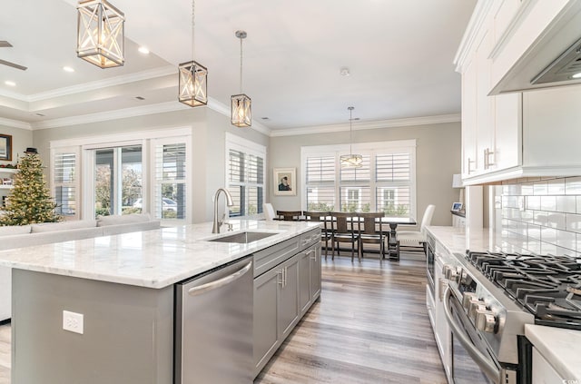 kitchen with appliances with stainless steel finishes, a kitchen island with sink, a healthy amount of sunlight, and range hood