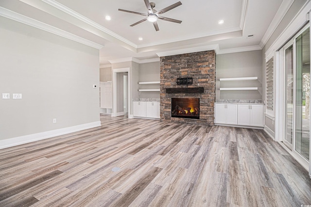 1201 Surf Pointe Dr, North Myrtle Beach, SC 29582 - unfurnished living room featuring light wood finished floors, ceiling fan, a tray ceiling, a fireplace, and crown molding