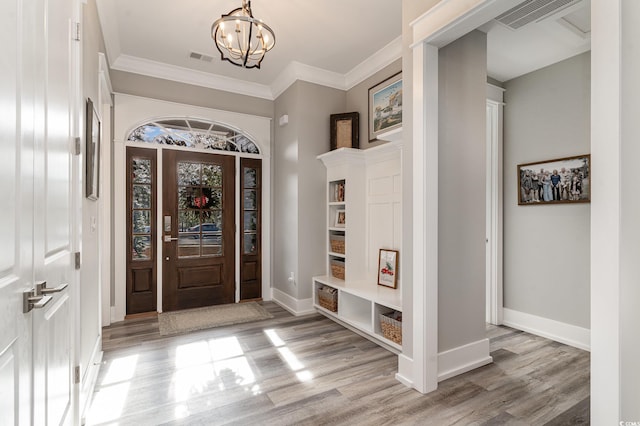 entrance foyer with light wood-type flooring, an inviting chandelier, and ornamental molding