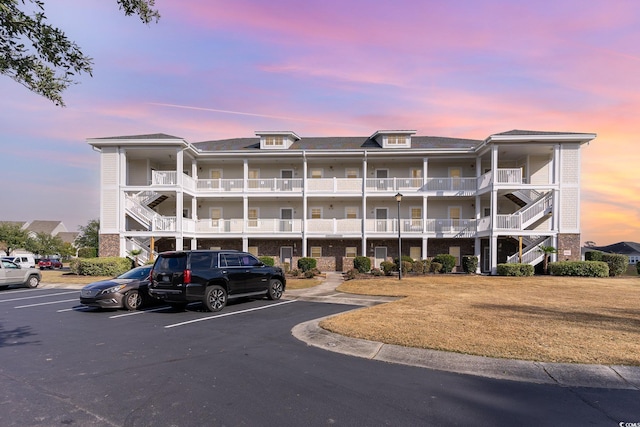 property at dusk with stairs and uncovered parking