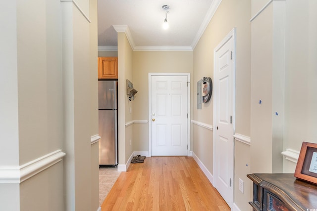 hallway with baseboards, light wood-style floors, and ornamental molding