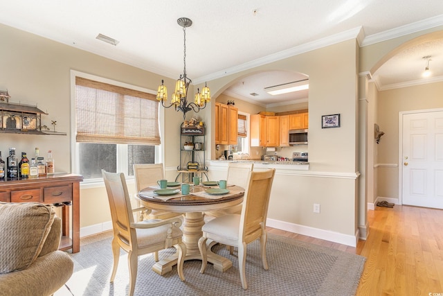 dining area featuring a wealth of natural light, light wood-style flooring, arched walkways, and a chandelier