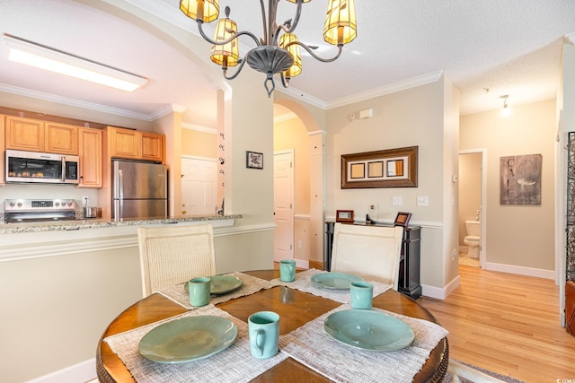 dining space with arched walkways, a chandelier, ornamental molding, and light wood finished floors