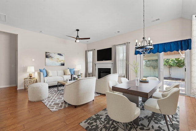 dining area featuring wood-type flooring and ceiling fan with notable chandelier