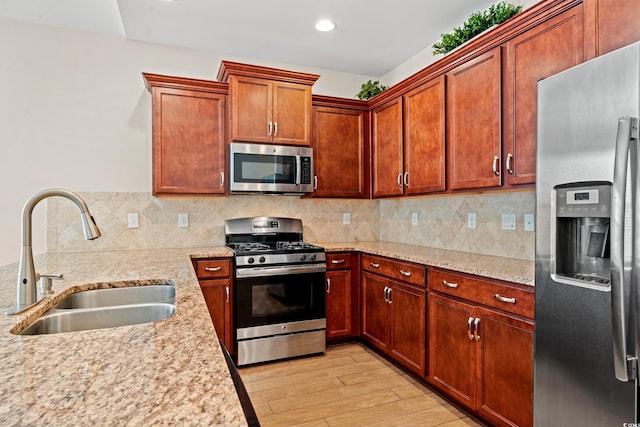 kitchen featuring sink, decorative backsplash, light wood-type flooring, light stone counters, and stainless steel appliances