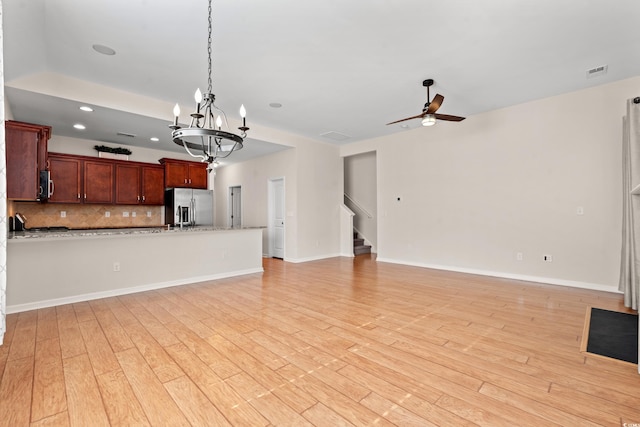 unfurnished living room featuring ceiling fan with notable chandelier and light hardwood / wood-style floors