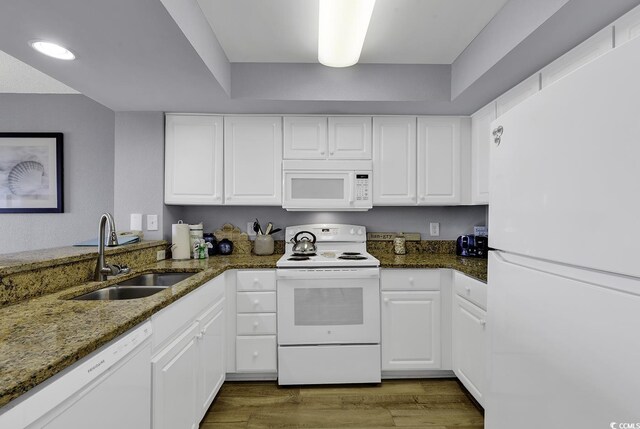 kitchen featuring white appliances, white cabinets, sink, light hardwood / wood-style floors, and kitchen peninsula