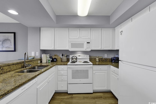 kitchen with dark stone counters, white appliances, white cabinets, and a sink