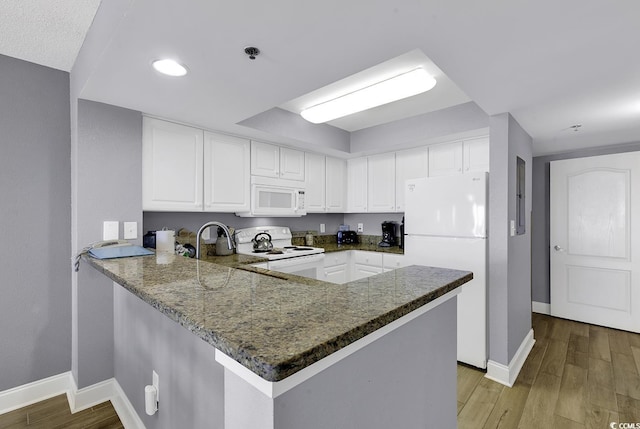 kitchen with light wood-style floors, white appliances, white cabinets, and a peninsula