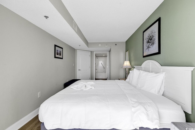 bedroom featuring ensuite bath, baseboards, and wood finished floors