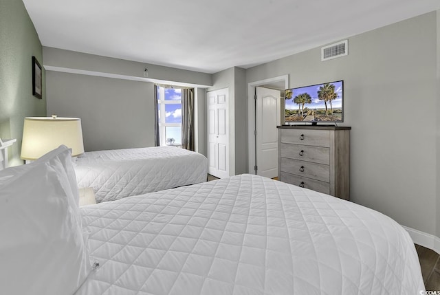 bedroom featuring baseboards, visible vents, and wood finished floors