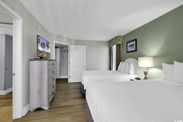 bedroom featuring baseboards, visible vents, and wood finished floors