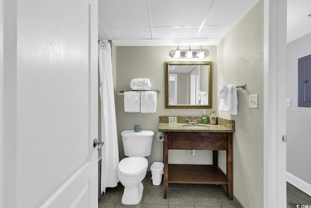 bathroom with baseboards, a drop ceiling, toilet, tile patterned floors, and vanity