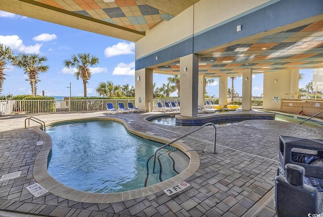 community pool with a patio area and fence