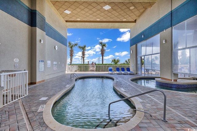 community pool with a patio area and fence