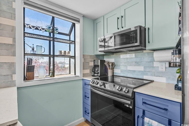 kitchen featuring a healthy amount of sunlight, light stone countertops, appliances with stainless steel finishes, and tasteful backsplash