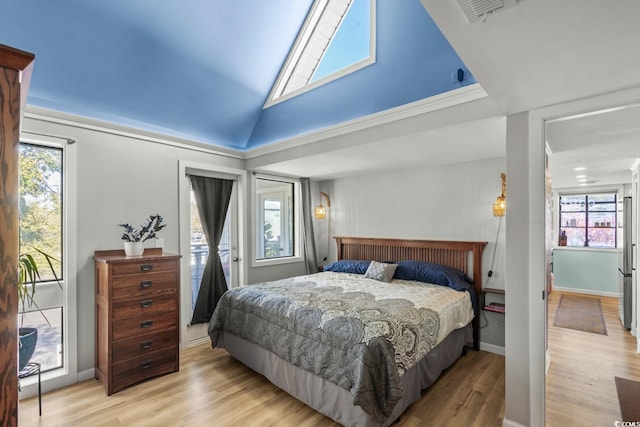 bedroom with multiple windows, crown molding, vaulted ceiling, and light wood-type flooring