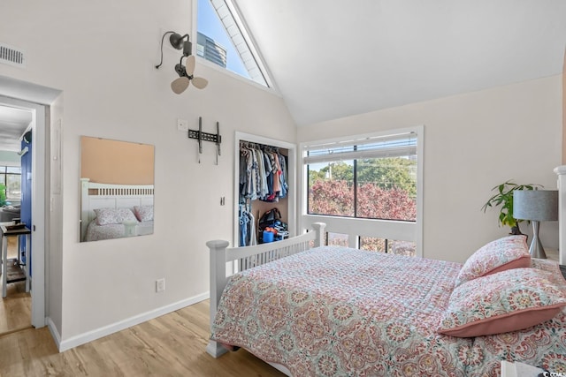 bedroom with multiple windows, a closet, high vaulted ceiling, and light hardwood / wood-style flooring