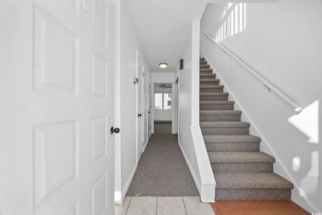 stairway with carpet flooring and a textured ceiling