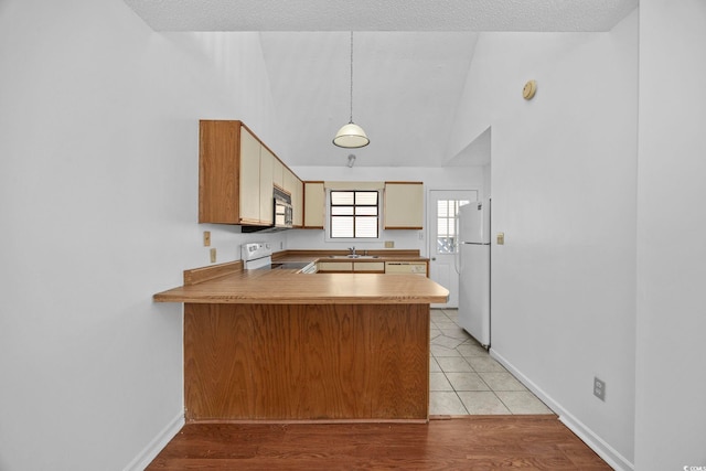 kitchen with kitchen peninsula, light wood-type flooring, white appliances, a textured ceiling, and pendant lighting