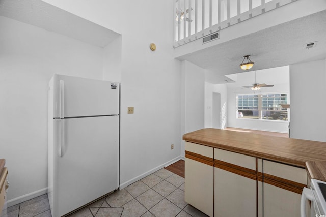 kitchen with white appliances, white cabinets, ceiling fan, light tile patterned floors, and a textured ceiling