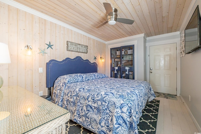 bedroom featuring ornamental molding, wood ceiling, ceiling fan, wooden walls, and hardwood / wood-style floors