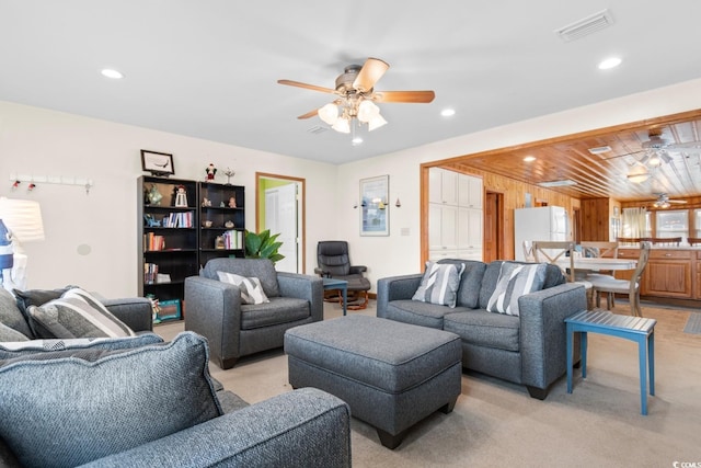 carpeted living room with ceiling fan and wooden walls