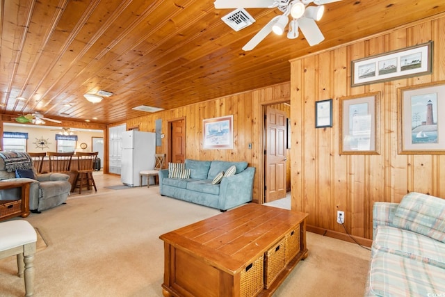 carpeted living room with ceiling fan, wood walls, and wood ceiling